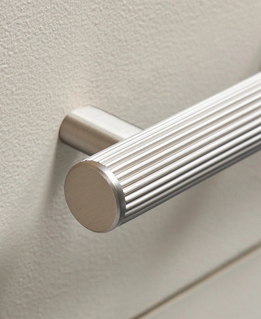dull silver ribbed kitchen cupboard handle on a cool neutral drawer