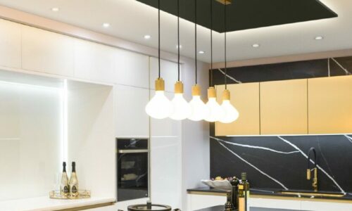 gold lanesborough multi-pendant light suspended above an induction hob an a black and white marble kitchen island