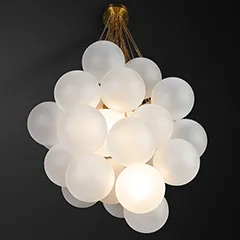 Bubble Chandelier with gold chain hanging from black ceiling