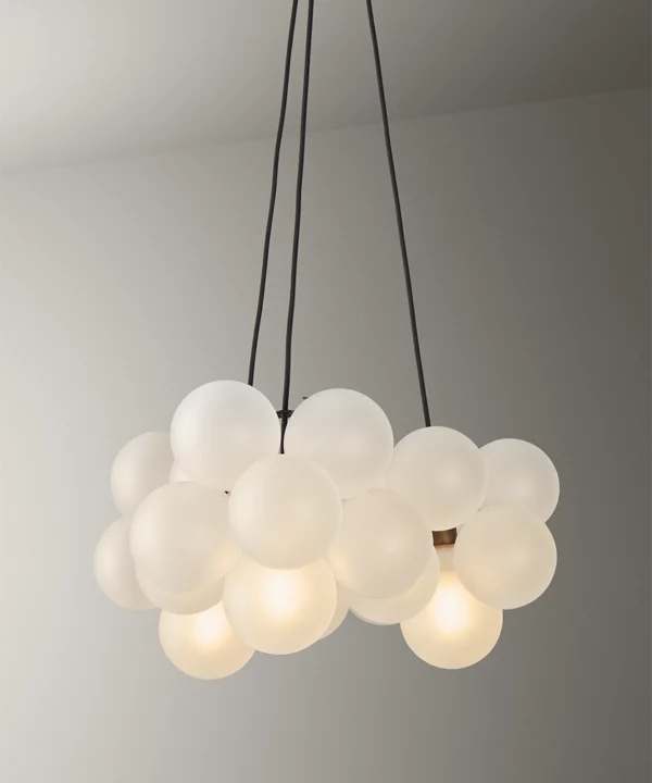 modern chandelier bubble ceiling light with frosted baubles, fabric cable and antique brass hardware shot on a warm grey background