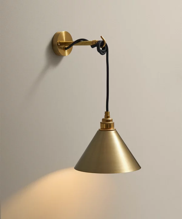industrial style wall light with hand spun metal shade in gold, gold mountings and black fabric cable in a drape and drop style