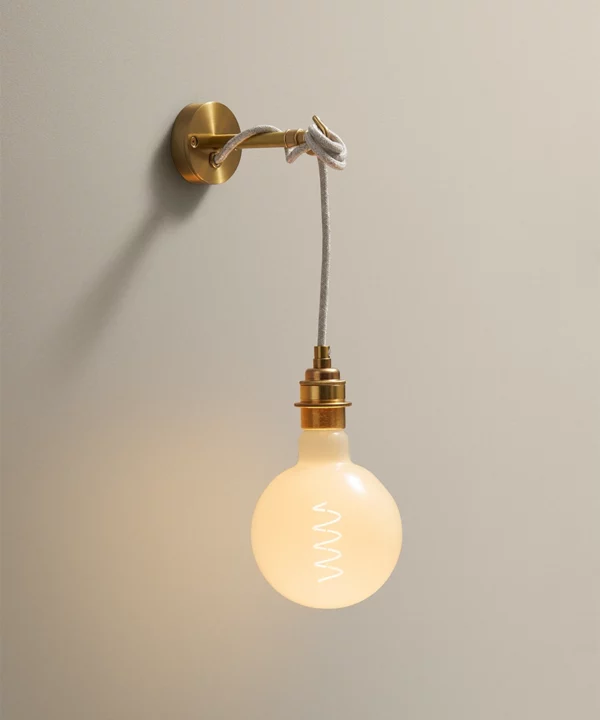 gold metal wall light bedside lamp shown with a large opaque light bulb