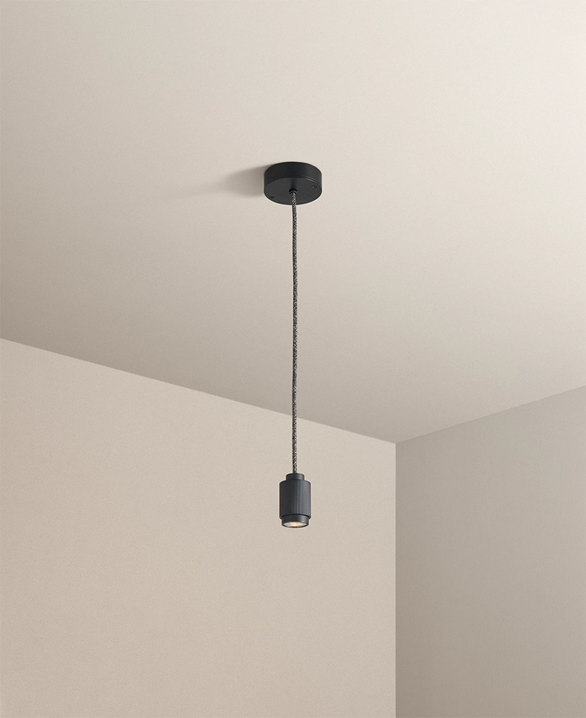 industrial style black spotlight pendant hanging from a taupe ceiling