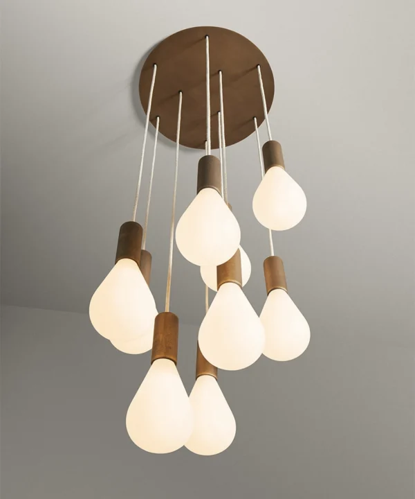 antique brass metal work cascade light for stairwells featuring linen fabric cable and opaque teardrop-shaped bulbs