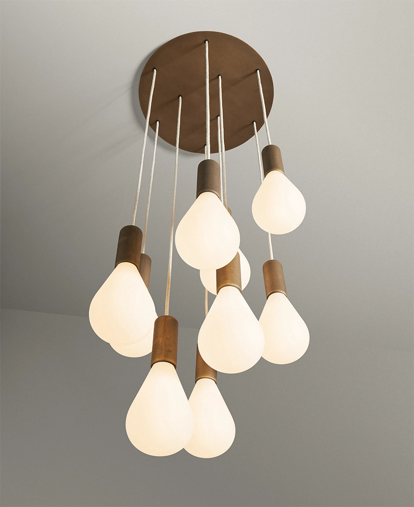 antique brass metal work cascade light for stairwells featuring linen fabric cable and opaque teardrop-shaped bulbs