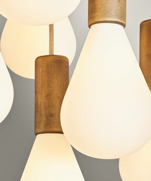 close up detail of opaque teradrop-shaped bulbs with antique brass bulb holders and linen fabric cable