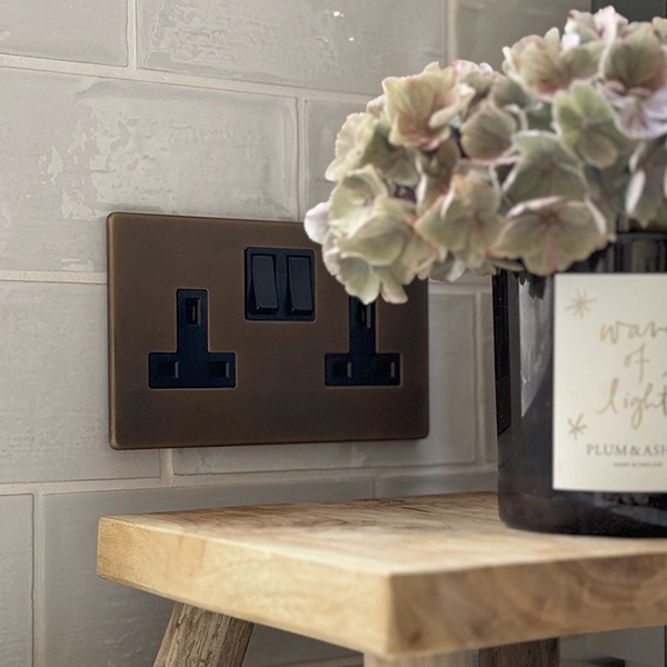 antique brass double socket on a tiled splashback
